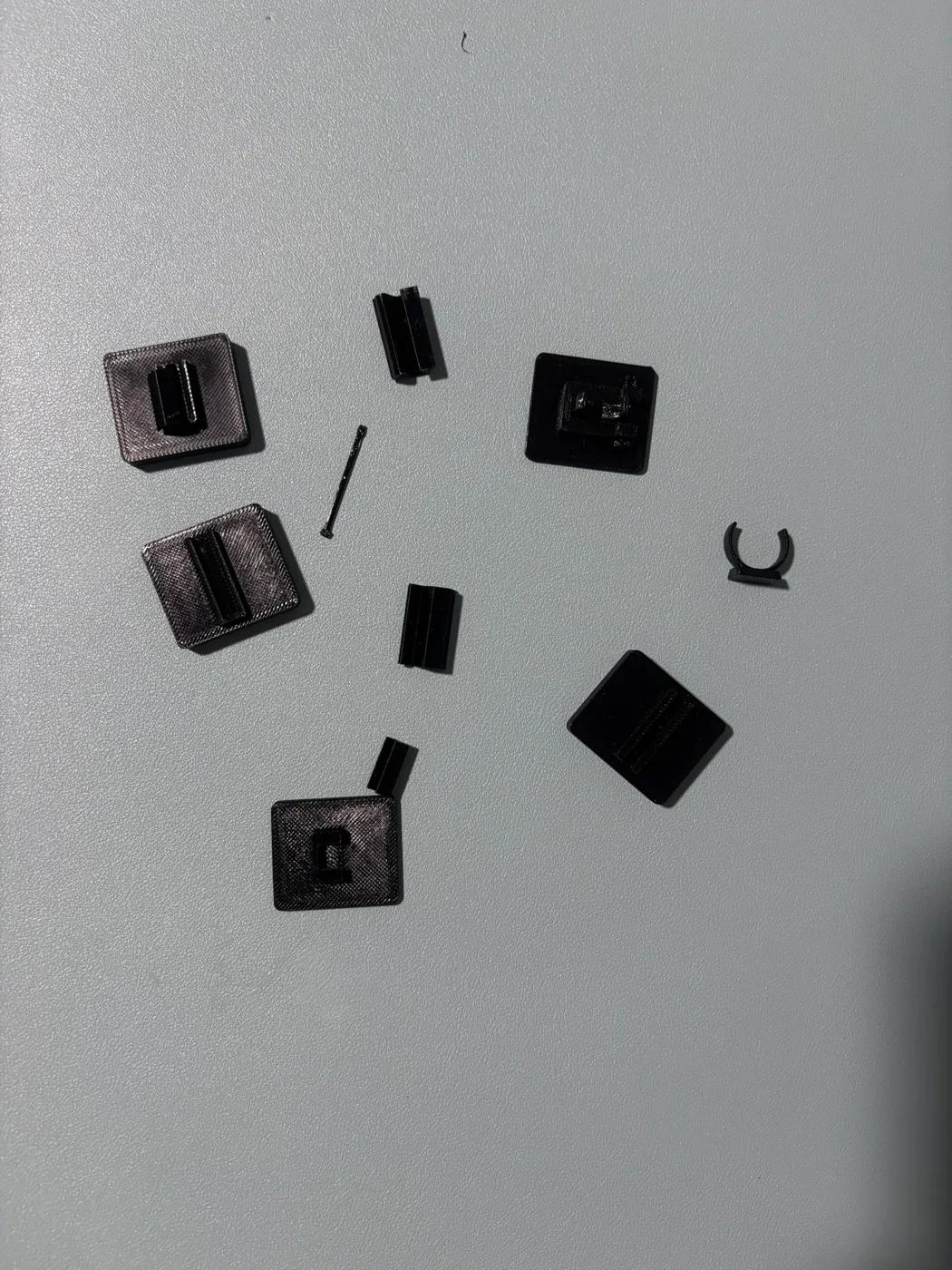 Small printed socket samples, connectors, a pin, and a curved pen clip arranged on a desk.